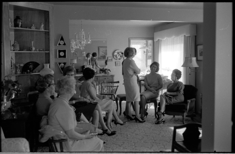 A photo of a group of women gathered in a sitting room. The event appears to be a bridal shower. Associated with item numbers: ce_b83_f1-item1-001 through ce_b83_f1-item1-016.