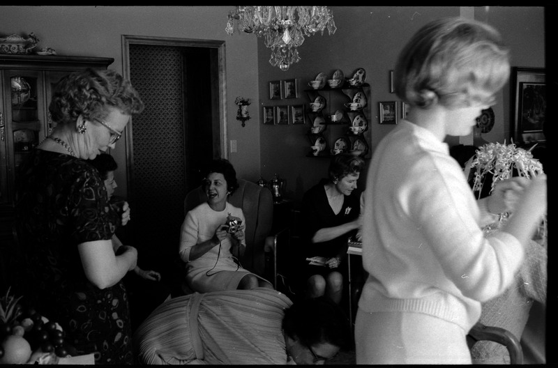 A photo of a group of women gathered in a sitting room. The event appears to be a bridal shower. Associated with item numbers: ce_b83_f1-item1-001 through ce_b83_f1-item1-016.
