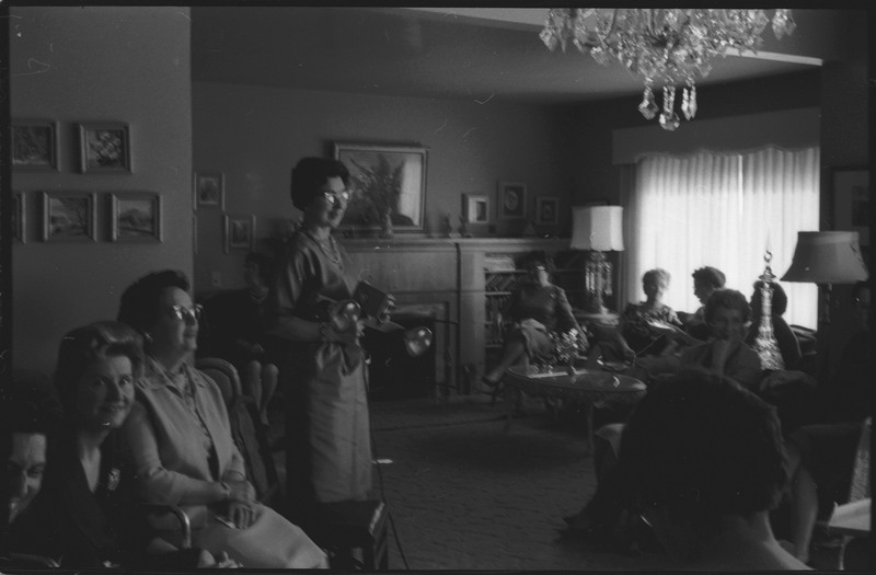 A photo of a group of women gathered in a sitting room. The event appears to be a bridal shower. Associated with item numbers: ce_b83_f1-item1-001 through ce_b83_f1-item1-016.