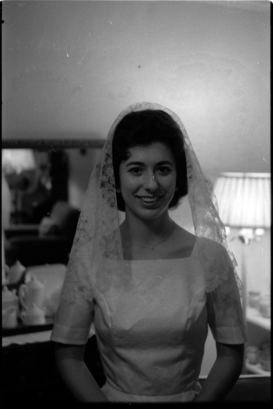 A photo of a woman wearing a wedding dress and smling for the camera. Associated with item numbers: ce_b83_f1-item1-017 through ce_b83_f1-item1-036.