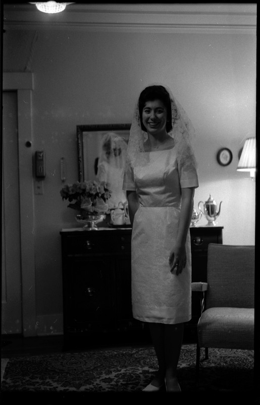 A photo of a woman wearing a wedding dress and smling for the camera. Associated with item numbers: ce_b83_f1-item1-017 through ce_b83_f1-item1-036.