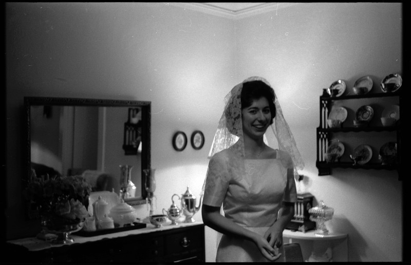 A photo of a woman wearing a wedding dress and smling for the camera. Associated with item numbers: ce_b83_f1-item1-017 through ce_b83_f1-item1-036.