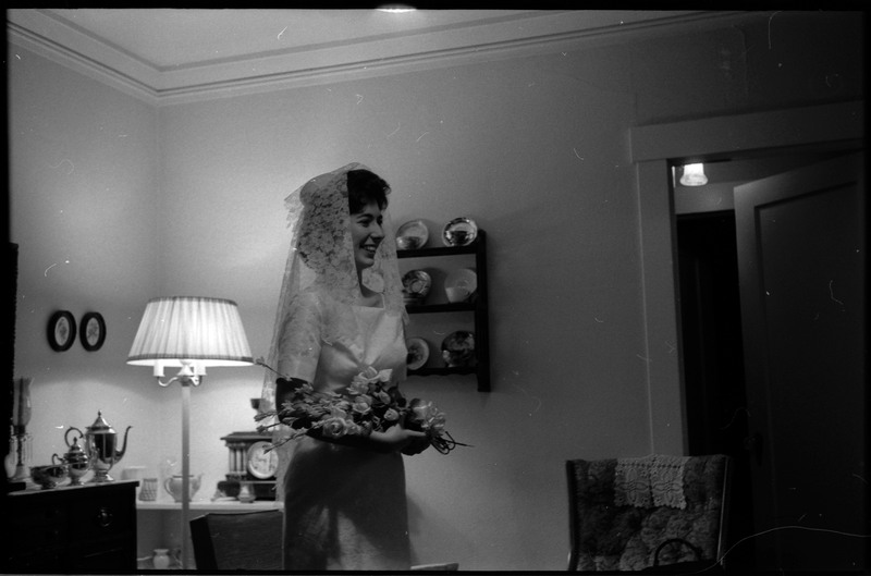 A photo of a woman wearing a wedding dress, holding a bouquet of flowers, and smiling for another camera. Associated with item numbers: ce_b83_f1-item1-017 through ce_b83_f1-item1-036.