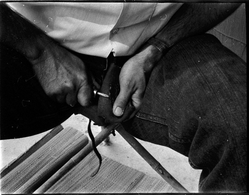 A photo of pair of hands, holding a stone and actively flintknapping. Associated with item numbers: ce_b83_f2-item1-004 through ce_b83_f2-item1-024.
