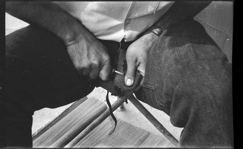 A photo of pair of hands, holding a stone and actively flintknapping. Associated with item numbers: ce_b83_f2-item1-004 through ce_b83_f2-item1-024.