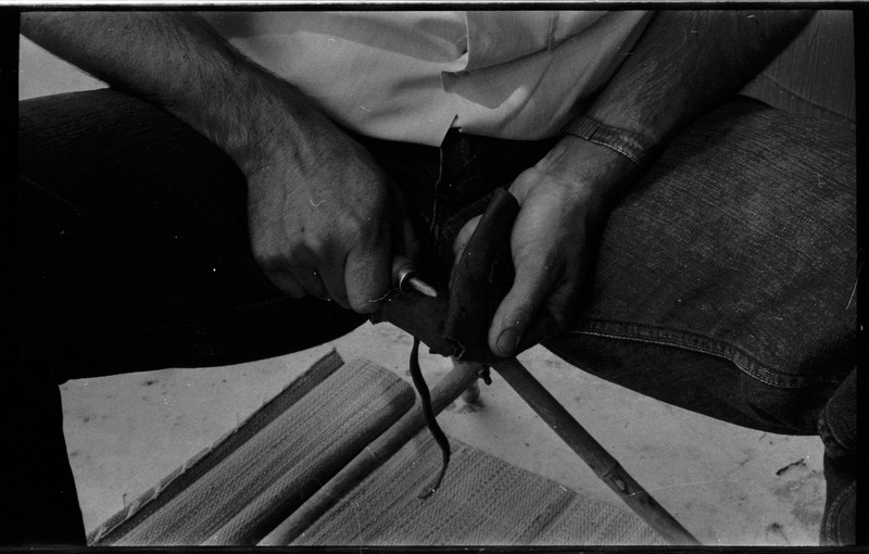 A photo of pair of hands, holding a stone and actively flintknapping. Associated with item numbers: ce_b83_f2-item1-004 through ce_b83_f2-item1-024.