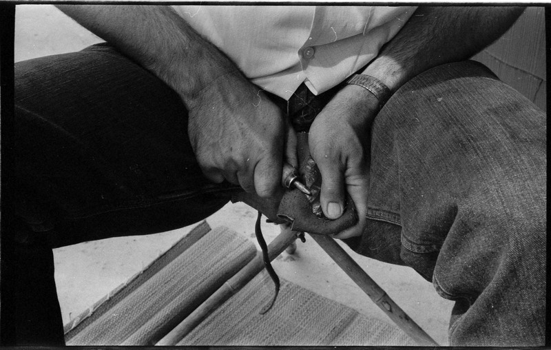 A photo of pair of hands, holding a stone and actively flintknapping. Associated with item numbers: ce_b83_f2-item1-004 through ce_b83_f2-item1-024.