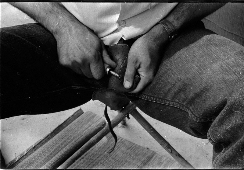 A photo of pair of hands, holding a stone and actively flintknapping. Associated with item numbers: ce_b83_f2-item1-004 through ce_b83_f2-item1-024.