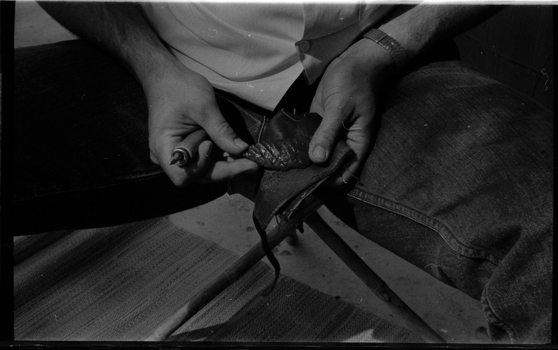 A photo of a pair of hands, holding a flintknapped piece and flintknapping tools. Associated with item numbers: ce_b83_f2-item1-004 through ce_b83_f2-item1-024.