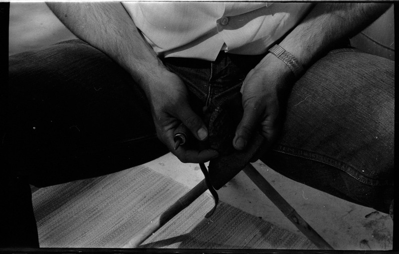 A photo of a pair of hands, holding a flintknapped piece and flintknapping tools. Associated with item numbers: ce_b83_f2-item1-004 through ce_b83_f2-item1-024.