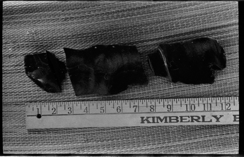 A photo of three flintknapped pieces next to a ruler.