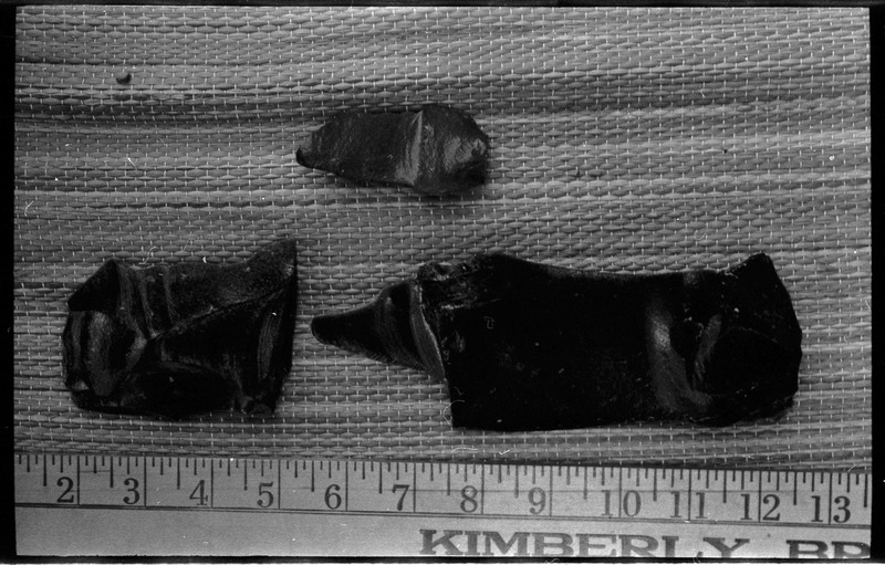 A photo of three flintknapped pieces next to a ruler.