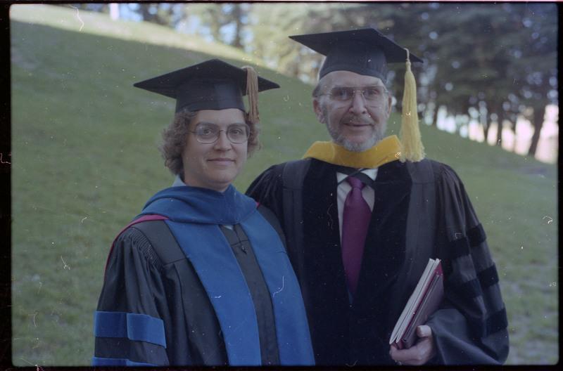 A photo of Donald Crabtree and Ruthann Knudson at graduation at the University of Idaho. Both are wearing caps and gowns.
