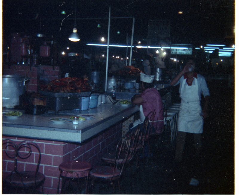 A photo of a food counter with at least two people in the image.
