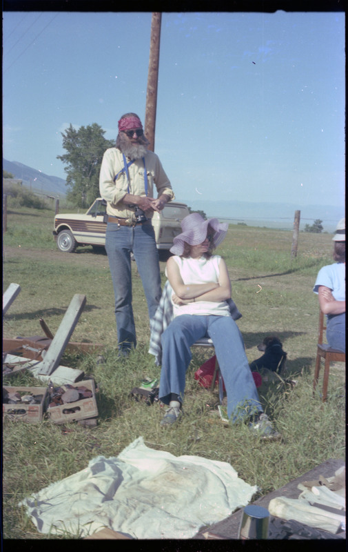 A photo of two people sitting outside, with a ground-level table of tools and materials. Associated item numbers: ce_b83_f2-item4-029 and ce_b83_f2-item4-031 through ce_b83_f2-item4-042.