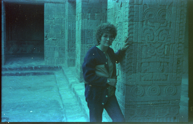 A photograph of Evelyn Crabtree standing next to a carved stone pillar.