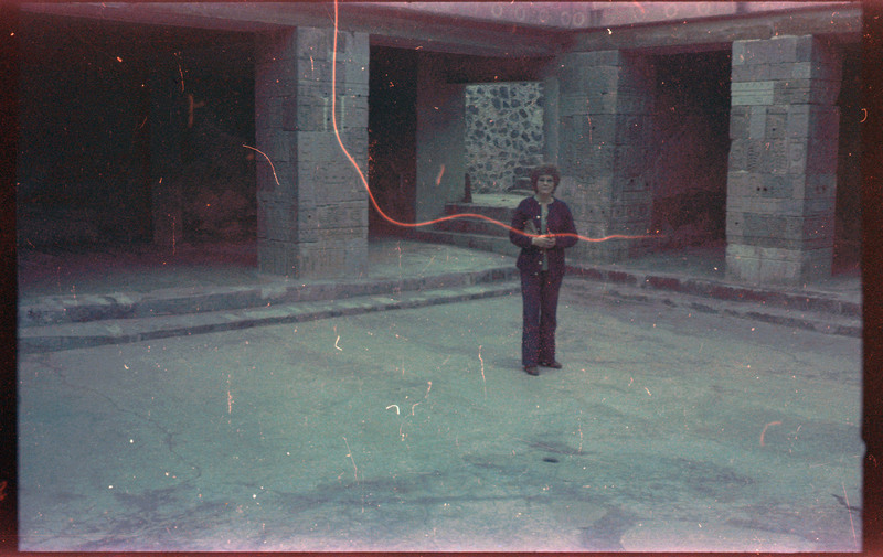 A photograph of Evelyn Crabtree standing in the center of a square, surrounded by stone pillars.