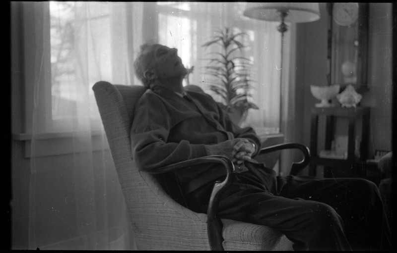 A photograph of a man, who appears to be sleeping, in a sitting or living room.