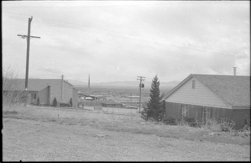 A photograph of a home and church, with other buildings in the distance.