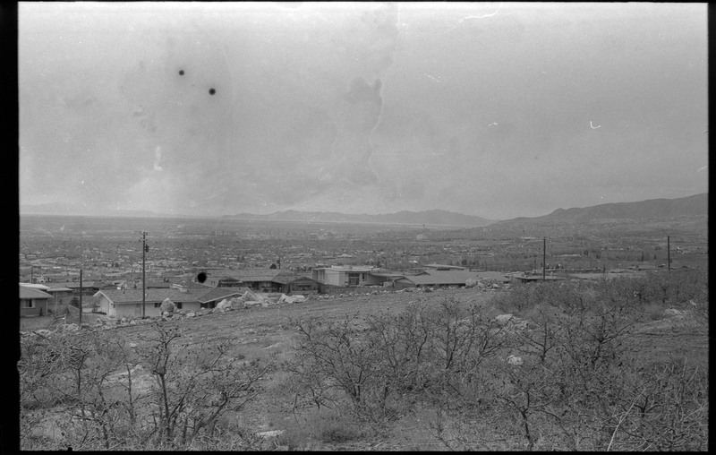 A photograph of undeveloped land with houses and other buildings in the distance.