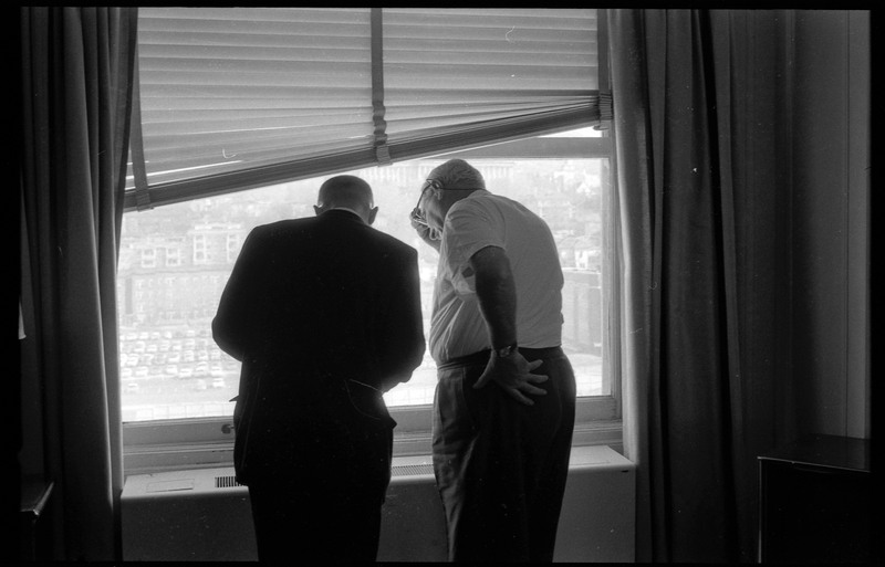 A photograph of Donald Crabtree and an unnamed man standing and looking at an object with their backs facing the camera.