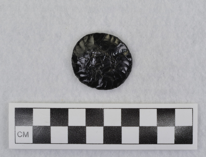 Spheroid/plano-convex indentation on plano side, "Due to pecking from tool engraver (electric). Crabtree was probably going to perforate this to be used as a pendant. See Crabtree 1472, pg 31 (cone principal paper). (JW) Tebiwa, Vol. 15, No. 2, 1972, pp. 29-42."