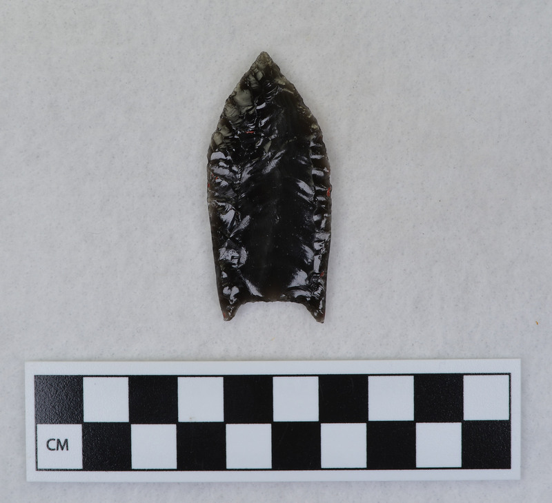 A Folsom point created by Donald E. Crabtree from obsidian from California. The object has been flaked and the margins are ground. Dr. Robert Lee Sappington describes the object as a "complete 'classic' Folsom point." This was a part of Crabtree's personal exhibit.