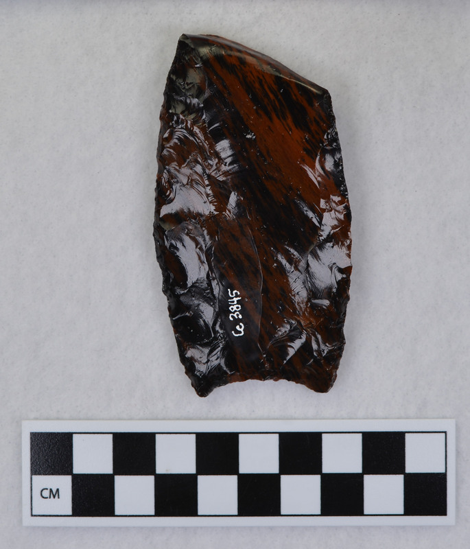 A Clovis point created by Donald E. Crabtree. This object mends with seven other objects in the collection; Ce.3846 - Ce.3852. The object was made using percussion fluting with a hammerstone while the distal end rested on an anvil.