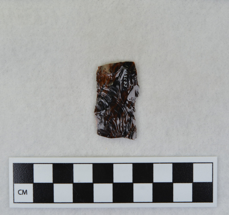 A channel flake, proximal end, from a Clovis point created by Donald E. Crabtree. This object mends with seven other objects in the collection; Ce.3845 - Ce.3852. The object was made using percussion fluting with a hammerstone while the distal end rested on an anvil. Ce.3847, Ce.3848, and Ce.3849 make up the channel flake from the labeled side of the object.