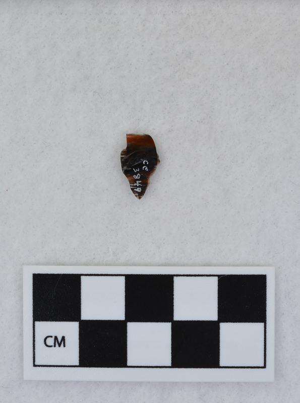 A channel flake, distal end, from a Clovis point created by Donald E. Crabtree. This object mends with seven other objects in the collection; Ce.3845 - Ce.3852. The object was made using percussion fluting with a hammerstone while the distal end rested on an anvil. Ce.3847, Ce.3848, and Ce.3849 make up the channel flake from the labeled side of the object.