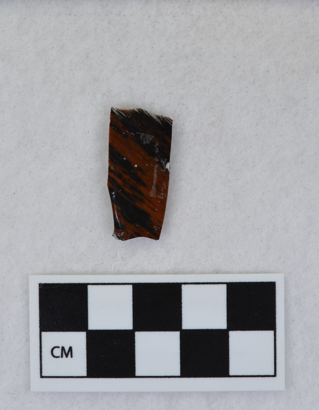 A channel flake, medial section, from a Clovis point created by Donald E. Crabtree. This object mends with seven other objects in the collection; Ce.3845 - Ce.3852. The object was made using percussion fluting with a hammerstone while the distal end rested on an anvil. Ce.3850, Ce.3851, and Ce.3852 make up the channel flake from the unlabeled side of the object.