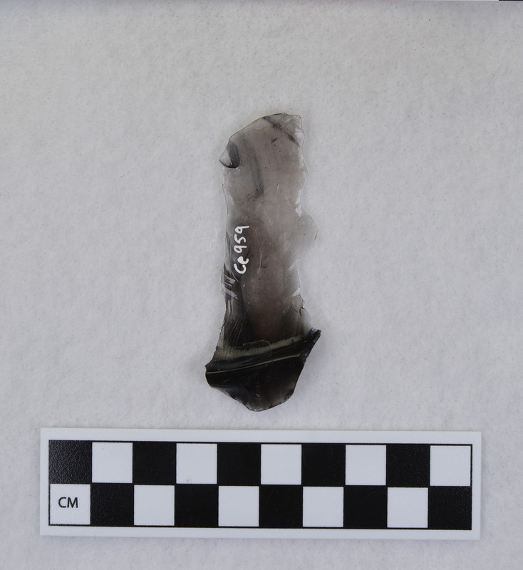A fluting error from Donald E. Crabtree's early fluting experiments. This is a channel flake connected to the distal end of Clovis point. The Clovis point was ground and rested on anvil. The channel flake and tip were removed when too much downward motion was initiated while attempting to flute the point. (JW) Mends with Ce.1067 and Ce.1068.
