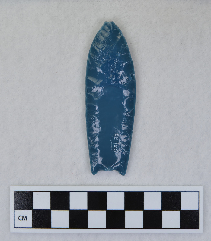 A Folsom point created by Donald E. Crabtree during his Folsom experiments. Created from light blue art glass, this point is lightly ground on the channel flake platforms.