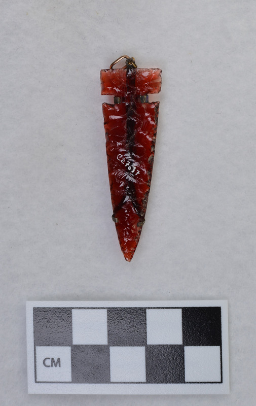 Donald E. Crabtree made this side notched biface out of red glass. He mounted the biface for a necklace.