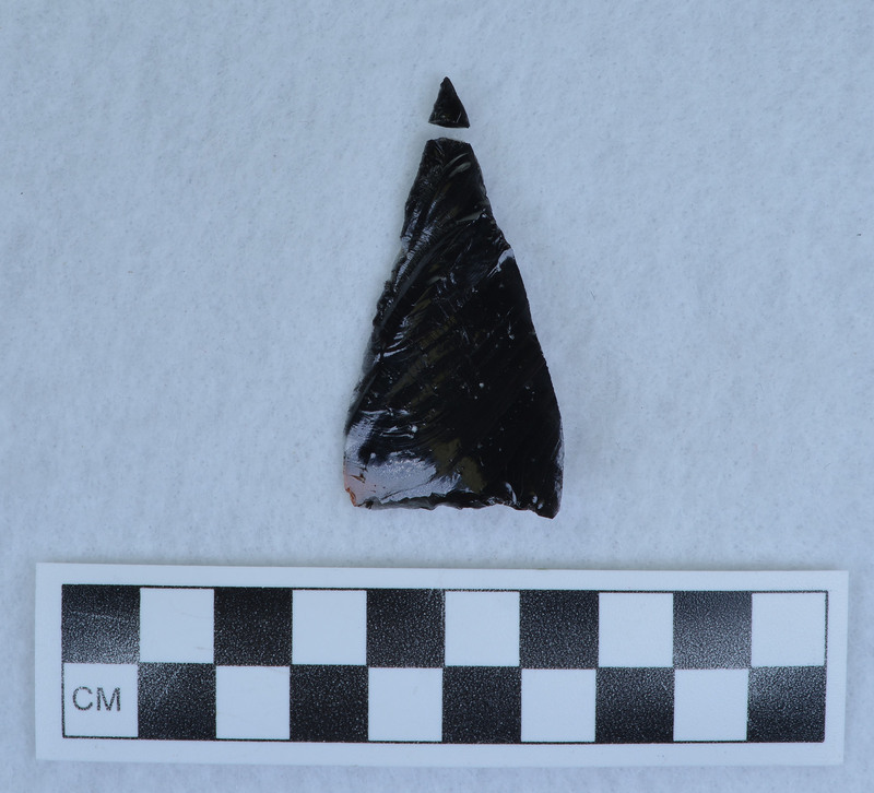 Flake altered slightly to form triangular point, Tip broken, glued. (MAP)