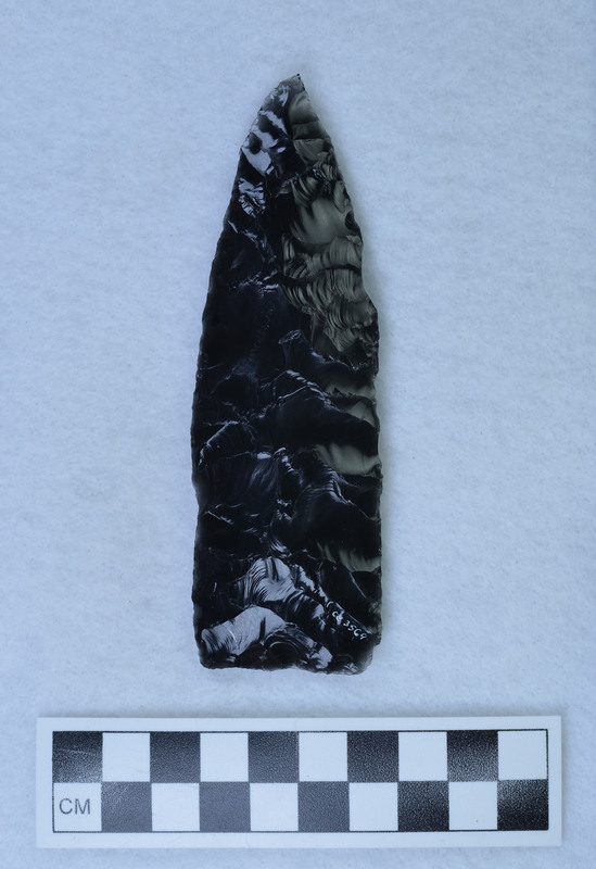 An unfinished obsidian biface created by Donald E. Crabtree. The completed side has flakes running margin to margin, with one flake exceeding the margin (outrepasse in French). The object is also signed by Crabtree. On the unfinished side "percussion" is etched. (JW)