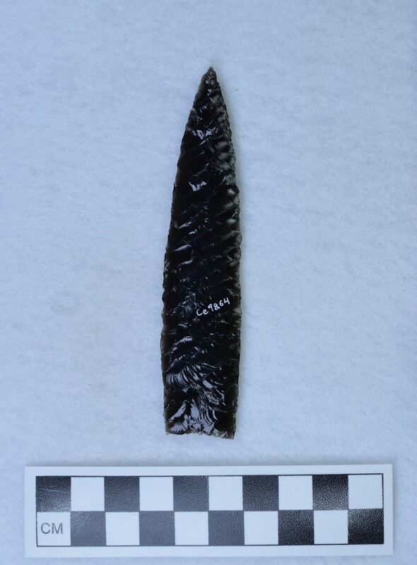 A biface created using two different methods by Donald E. Crabtree using obsidian from Glass Butte, Oregon. He often did this to compare the quality of the flake produced by the two styles. On one side, palm held pressure flaking was used, and the other side is finger held (Titmus flaking). Most of these points with both techniques were made between 1970-78. (JW)