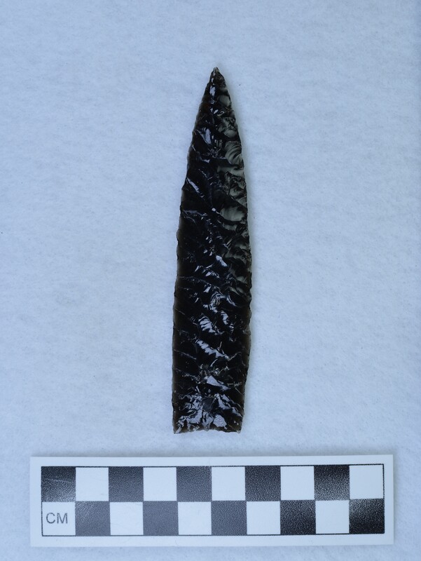 A biface created using two different methods by Donald E. Crabtree using obsidian from Glass Butte, Oregon. He often did this to compare the quality of the flake produced by the two styles. On one side, palm held pressure flaking was used, and the other side is finger held (Titmus flaking). Most of these points with both techniques were made between 1970-78. (JW)