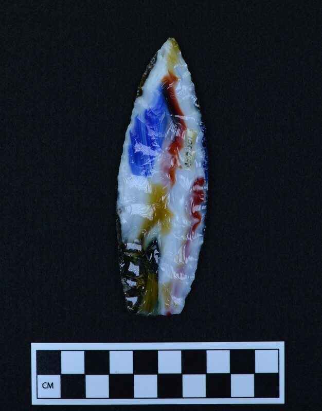 This lanceolate style point was made by Donald E. Crabtree using marbled art glass. The basal margins (base edges) were ground and thinned. The biface is made up of large collateral flakes.