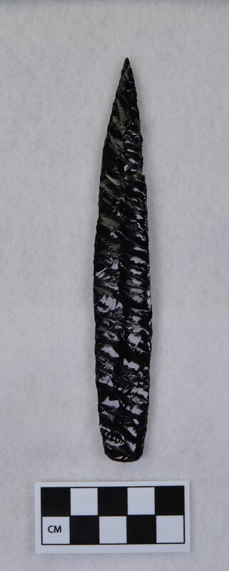 Parallel diagonal flaking, broken/glued in multiple places, lanceolate style, basal margins ground and thinned. May be glass, not obsidian. (MAP)