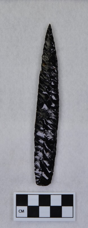 Parallel diagonal flaking, broken/glued in multiple places, lanceolate style, basal margins ground and thinned. May be glass, not obsidian. (MAP)