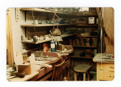 The front of a postcard decorated with a picture of an indoor lithic workshop.