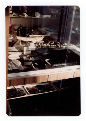 The front of a postcard decorated with a picture of a shelf filled with lithic artifacts.