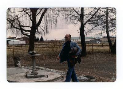 The front of a postcard decorated with a picture of a man walking across a yard.