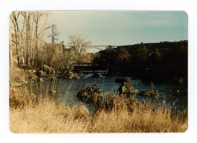 The front of a postcard decorated with a picture of a river spanned by a bridge.