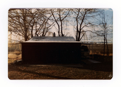 The front of a postcard decorated with a picture of a housed shaded by sunset.