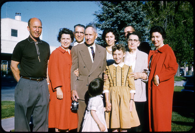 A photographic slide displaying a group of people standing closely together in front of a SEARS store. Four men, four women, and two children face the camera smiling.