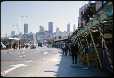 A photographic slide of an urban center with pedestrians in front of a cityscape. Don E. Crabtree is standing in the foreground.