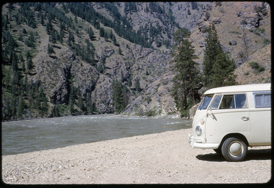 A photographic slide of a van on the shore of a river.