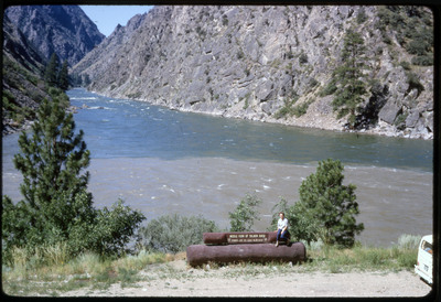 A photographic slide of Evelyn Crabtree sitting in front of the middle fork of the Salmon River.